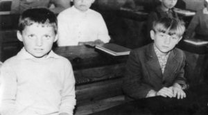 czarno -białe zdjęcie przedstawia uczniów w ławkach