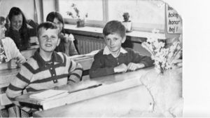 czarno -białe zdjęcie przedstawia uczniów w ławkach