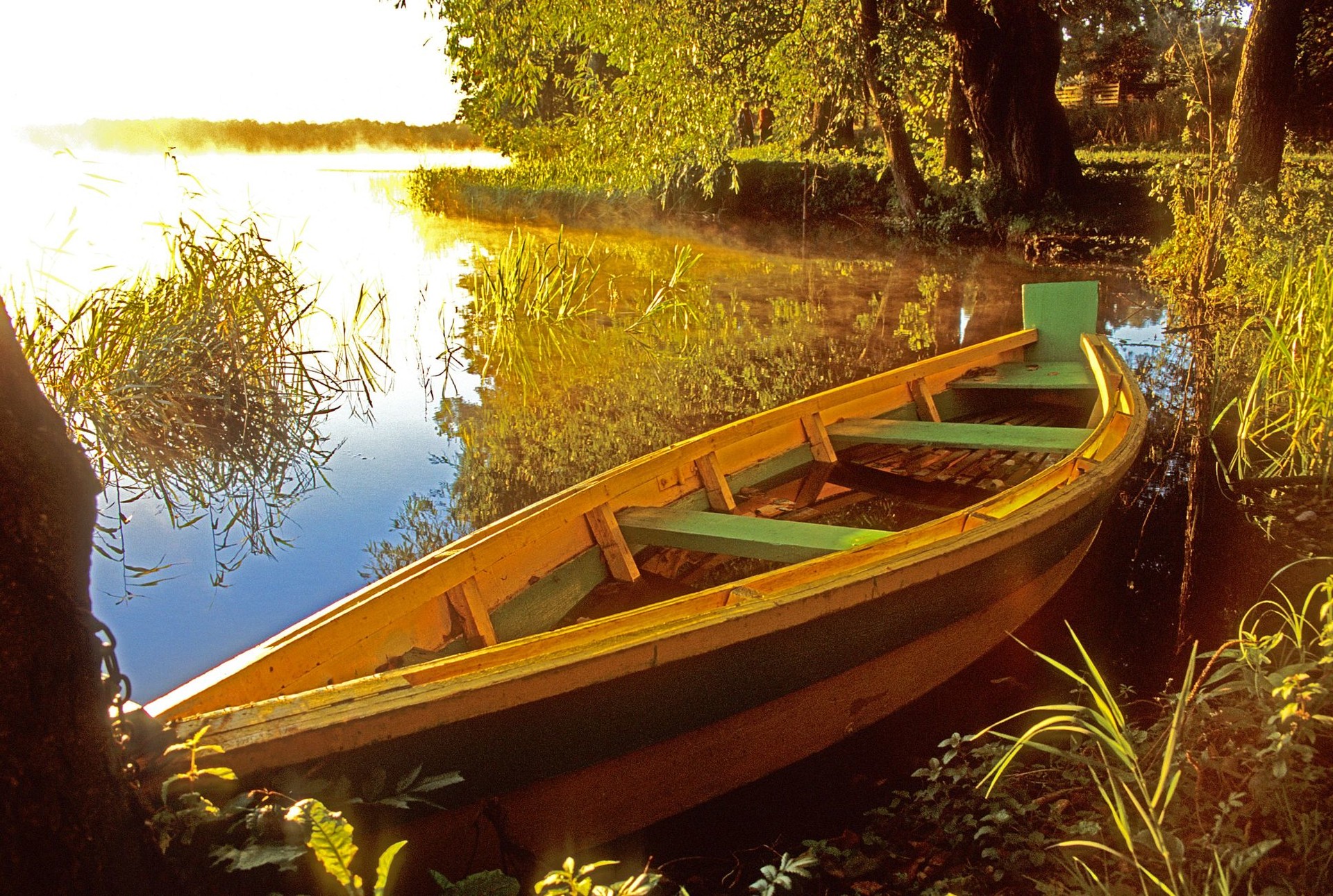 Zdjęcie łódki na jeziorze przy brzegu o wschodzie słońca